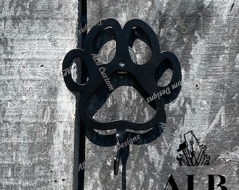 Pode incluir: Gancho de metal preto em forma de pata com o texto "ALB Custom Designs" no lado. O gancho está montado em uma superfície de madeira.