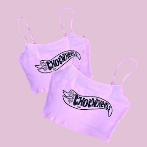 May include: Two pink spaghetti strap crop tops with the text "Hot Wheels" printed in black on the front. The text is stylized with a banner and stars.