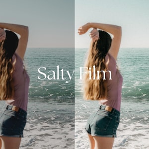 May include: A woman with long brown hair is standing on a beach with her arms raised above her head. She is wearing a pink shirt and denim shorts. The ocean is in the background. The text "Salty Film" is superimposed on the image.