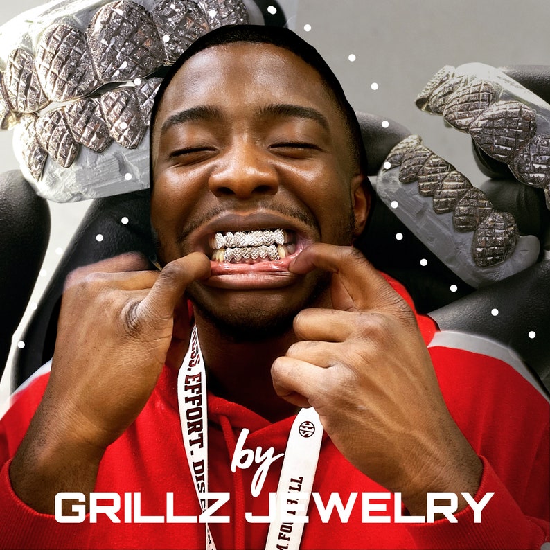 Puede incluir: Una persona que lleva una camisa roja con un cord&oacute;n blanco que dice "Grillz Jewelry" y tiene una parrilla de diamantes en la boca.