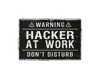 May include: A rectangular black sign with white text that reads "WARNING HACKER AT WORK DON'T DISTURB". The sign has a distressed, weathered appearance, with a white border.