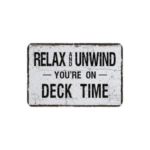 May include: Rectangular white sign with black text that reads "RELAX AND UNWIND - YOU'RE ON - DECK TIME." The sign has a distressed, weathered appearance with a black border.