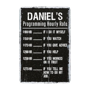 May include: A rectangular black sign with white text that reads "DANIEL'S Programming Hourly Rate." The sign lists hourly rates from $100 to $275 based on the level of assistance provided. The sign has a distressed, vintage appearance.