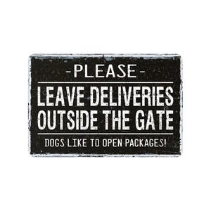May include: A rectangular black and white sign with the text "PLEASE LEAVE DELIVERIES OUTSIDE THE GATE" and "DOGS LIKE TO OPEN PACKAGES!" in a distressed font. The sign has a rustic, weathered appearance.