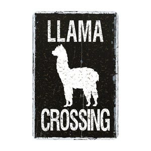 May include: A rectangular black metal sign with white text and a white llama silhouette. The text reads "LLAMA CROSSING" in a distressed font, suggesting a vintage or rustic style. The sign is likely for decorative purposes.