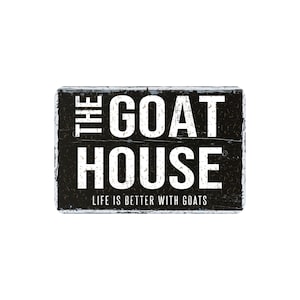 May include: A rectangular black sign with white text that reads "THE GOAT HOUSE" above "LIFE IS BETTER WITH GOATS". The sign has a distressed, rustic appearance with white paint around the edges.