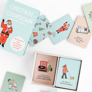 Könnte beinhalten: Ein hellblaues Kartenset mit Weihnachts-Countdown-Aktivitäten. Die Box und die Karten zeigen Illustrationen von Weihnachtsmännern, Weihnachtsbäumen und Urlaubsaktivitäten. Das Set enthält 36 illustrierte Karten für einen magischen Countdown zu Weihnachten.