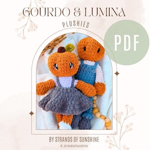 Puede incluir: Dos peluches de ganchillo titulados GOURDO & LUMINA PLUSHIES PDF BY STRANDS OF SUNSHINE. Uno tiene cabeza de calabaza naranja con tallo verde y viste un vestido gris. El otro tiene cabeza naranja y viste un peto azul sobre una camisa blanca.