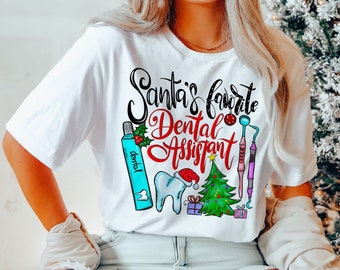 Könnte beinhalten: Weißes T-Shirt mit dem Text "Santa's favorite Dental Assistant" und zahnmedizinischen Grafiken. Das Design umfasst einen Zahn mit Weihnachtsmütze, einen Weihnachtsbaum und zahnärztliche Instrumente. Das Shirt wird von einer Person getragen.