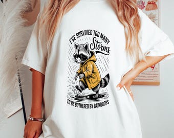 Camiseta "He sobrevivido a demasiadas tormentas", Camiseta divertida de mapache, Camiseta con cita sarcástica, Camiseta de regalo moderna para ella, Camiseta de regalo de mapache