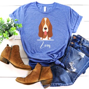 Peut inclure: Un t-shirt bleu avec une illustration de dessin anim&eacute; d'un basset hound avec le nom "Zeus" imprim&eacute; sous le chien.