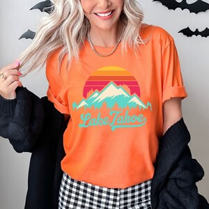May include: Orange t-shirt with a retro sunset graphic and mountains with the text "Lake Tahoe" in a blue and green font.
