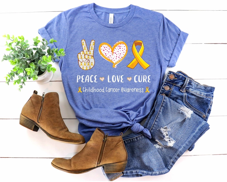 May include: A blue t-shirt with a peace sign, heart, and yellow ribbon. The text reads "Peace Love Cure Childhood Cancer Awareness".