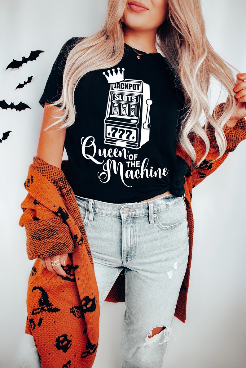 May include: A black t-shirt with a white graphic of a slot machine with the text "Jackpot Slots" and "Queen of the Machine".