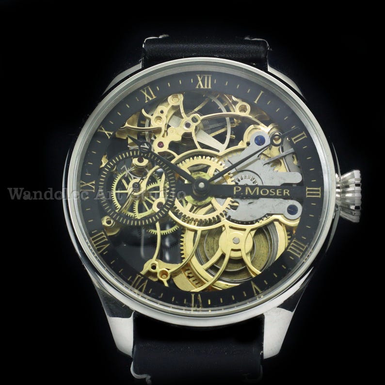 May include: A luxury wristwatch with a black face and a visible gold-colored mechanical movement. The watch has a silver-colored case, black leather band, and Roman numeral hour markers. The brand name "P. Moser" is visible on the face.
