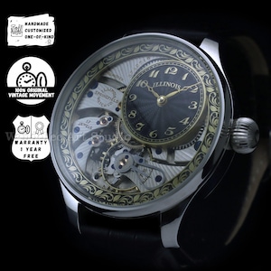 Puede incluir: Un reloj de pulsera Illinois Springfield Watch Co. plateado con esfera negra y manecillas y números dorados. El reloj presenta un intrincado diseño de esfera abierta, mostrando los engranajes y mecanismos internos. La correa es de cuero negro.