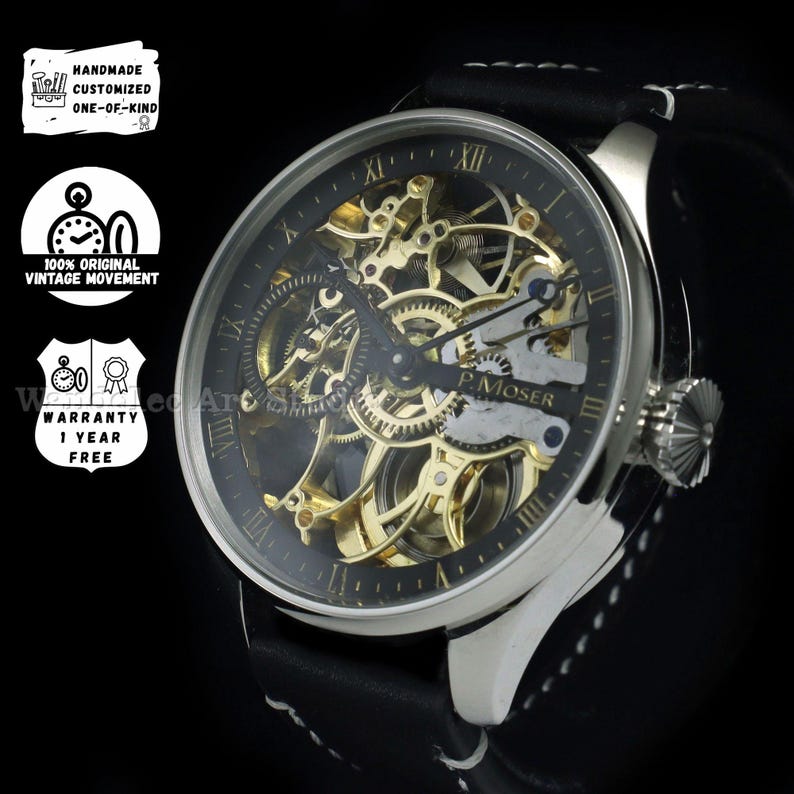 May include: A silver-toned wristwatch with a black face and a visible gold-colored mechanical movement. The watch has Roman numeral hour markers and a black leather band with white stitching. The watch face reads "P. Moser".