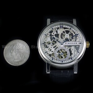 May include: A silver-toned skeleton watch with a black leather band. The watch face reveals intricate internal mechanisms and the brand name "P. MOSER". A U.S. quarter is next to the watch for size comparison. The watch has a gold-colored crown.