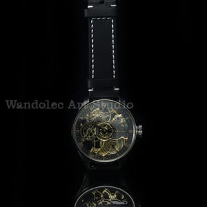 May include: A black wristwatch with a skeleton dial, showcasing the intricate inner workings. The watch has a black leather strap with white stitching. The watch face displays Roman numerals and the brand name "H. Moser". The watch is reflected in a dark surface.