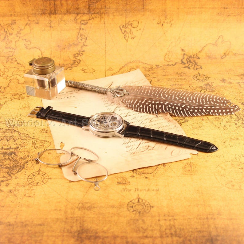 May include: A vintage-themed still life featuring a skeleton watch with a black leather band, an inkwell, a quill pen, and round eyeglasses. The items rest on a map-printed surface, creating an antique aesthetic. The watch face is visible, showcasing its intricate inner workings.