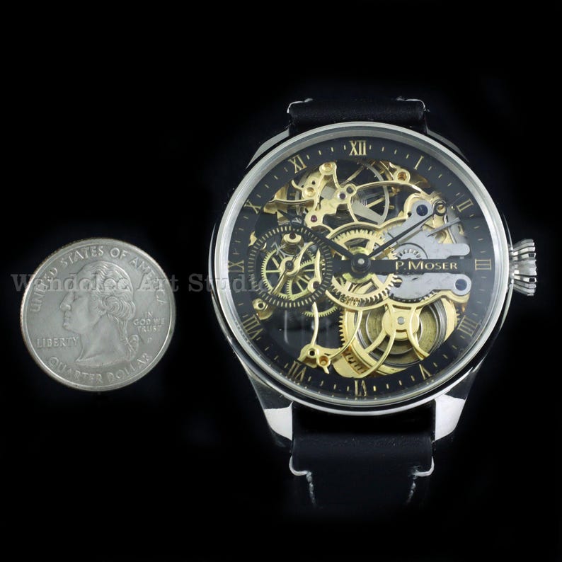 May include: A skeleton watch with a black face and gold-colored gears, featuring Roman numeral hour markers. The watch has a silver-colored case and a black leather band. A quarter is next to the watch for size comparison.