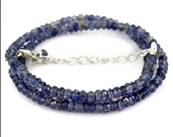 May include: A double-strand necklace made of small, faceted, dark blue gemstone beads. The necklace has a silver chain clasp.
