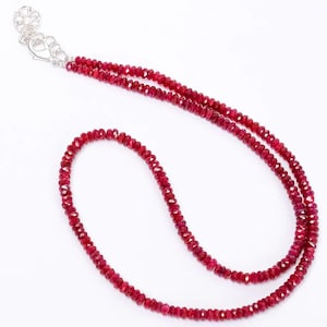 Könnte beinhalten: Eine doppelreihige Halskette aus kleinen, facettierten, roten Rubinperlen. Die Halskette hat einen silbernen Verschluss.