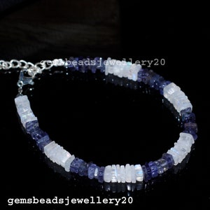 Può includere: Un braccialetto d'argento con perline di pietre preziose bianche e blu alternate. Il braccialetto è realizzato con perline di forma quadrata e ha una chiusura in argento.