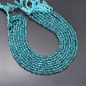 May include: Strands of small, faceted, light blue beads. The beads are strung together, forming multiple strands. The ends of the strands are tied with a matching light blue tassel. The beads have a slight sparkle.
