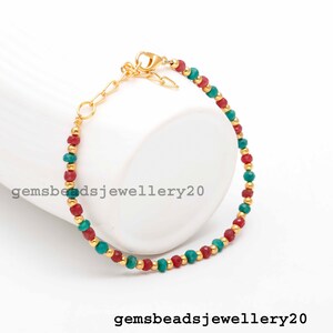 Könnte beinhalten: Goldfarbenes Armband mit abwechselnd roten und türkisfarbenen Perlen, unterbrochen von kleineren goldenen Perlen. Das Armband hat eine verstellbare Kette und einen Verschluss. Der Text "gemsbeadsjewellery20" ist sichtbar.