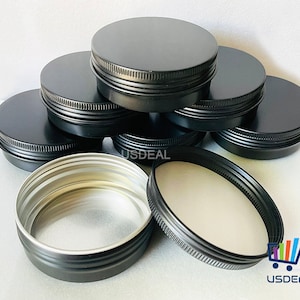 May include: A stack of black metal tins with silver lids. The tins are stacked in a pyramid shape. The lids are all closed.