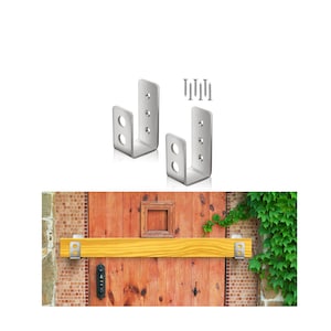 May include: Two silver metal brackets with screw holes, shown with screws. A wooden beam is mounted on a wooden door with the brackets.
