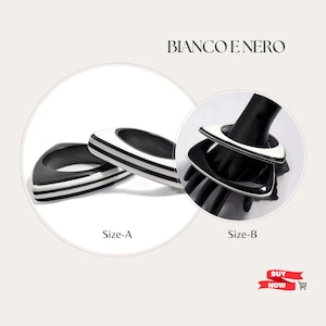May include: Two black and white geometric bangle bracelets, one is larger than the other. The bracelets are made of resin and have a glossy finish. The larger bracelet is labeled "Size-A" and the smaller bracelet is labeled "Size-B".
