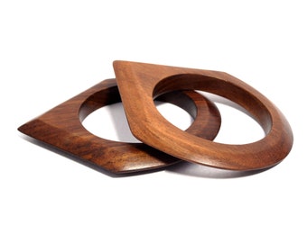 May include: Two wooden bangles, one on top of the other, both in a diamond shape with rounded edges. The bangles are a rich brown colour.