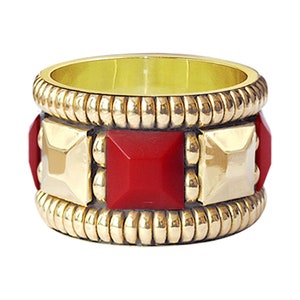 May include: A gold ring with a red stone and a textured band.