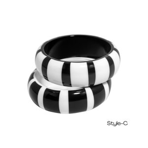 May include: Two black and white striped plastic bangles stacked on top of each other. Style-C.