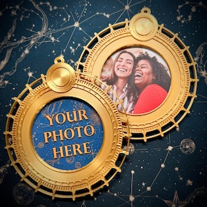 Op de afbeelding: Twee goudkleurige, cirkelvormige fotolijsten met een hemels ontwerp. Eén lijst toont een foto van twee lachende mensen, terwijl de andere de tekst "YOUR PHOTO HERE" op een blauwe achtergrond heeft. De lijsten staan tegen een donkerblauwe achtergrond met een sterrenbeeldpatroon.