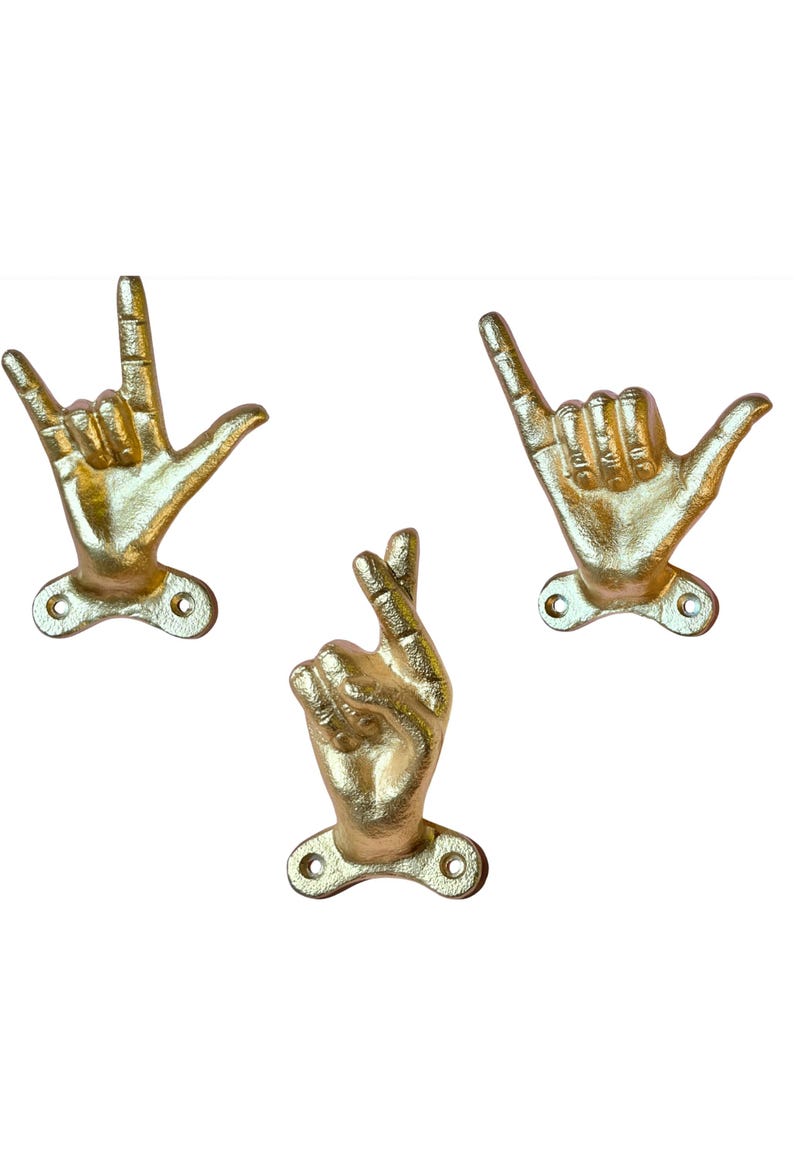 May include: Three gold-colored hand-shaped wall hooks. One hook forms the "I love you" sign, another the "rock on" sign, and the third the "hang loose" sign. Each hook has a small base with two screw holes for mounting.