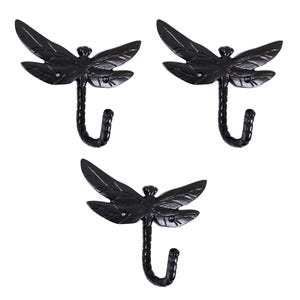 Może przedstawiać: Trzy czarne haczyki ścienne w kształcie ważki. Każdy haczyk ma kształt ważki ze szczegółowymi skrzydłami i zakrzywionym haczykiem do wieszania przedmiotów. Haczyki są wykonane z metalu i pasują do różnych stylów wystroju.