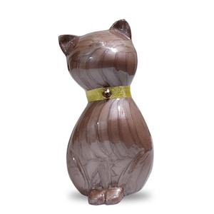 May include: A brown ceramic cat figurine with a gold ribbon around its neck. The cat is sitting with its head tilted to the side.