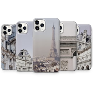May include: Set of five clear phone cases featuring different images of Parisian landmarks. The cases depict the Eiffel Tower, the Arc de Triomphe, and other Parisian architecture.