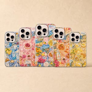 May include: Five phone cases with colorful Italian-themed designs. The cases feature images of food, drinks, and Italian landmarks. The cases are in various colors, including blue, pink, and orange. The cases are arranged in a row.