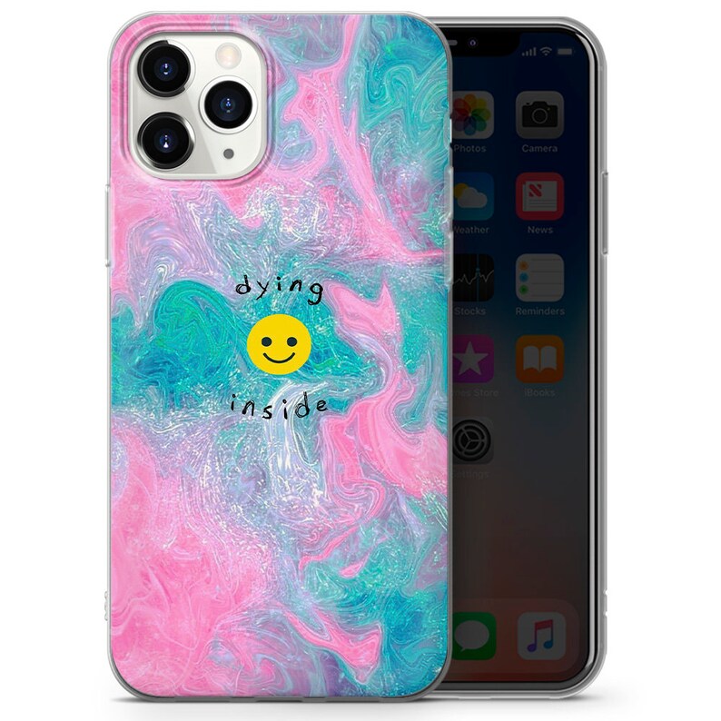 May include: A clear phone case with a pink, blue, and purple marbled design. The case has a yellow smiley face with the text "dying inside" written above it.