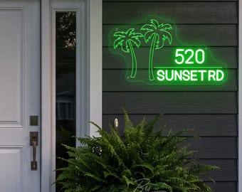 May include: A bright green neon sign mounted on dark gray horizontal siding. The sign features two palm tree silhouettes on the left and the text 520 SUNSET RD on the right, all enclosed within a clear, irregularly shaped acrylic backing.