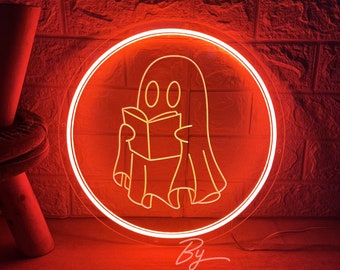 May include: A circular neon sign emitting a bright red glow, featuring a linear outline of a ghost holding an open book. The design is enclosed within a circular neon border. The text "By ZP JNeonCustom" is visible in white script at the bottom.