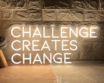 May include: A white neon sign against a textured brick wall. The sign reads "CHALLENGE CREATES CHANGE" in large, capital letters. The sign is lit up, and the text is bright. The sign is on a light-colored rug. The text "By ZP Neon Custom" is at the bottom.