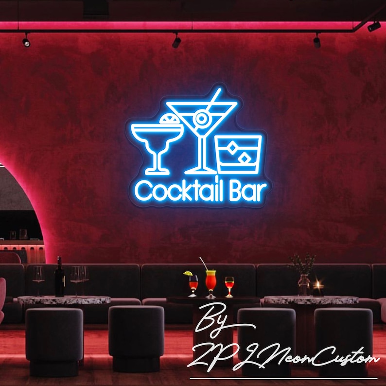 May include: A neon sign with a blue outline of three cocktail glasses and the words "Cocktail Bar" in white. The sign is mounted on a red wall. The image also shows a bar setting with seating and tables.