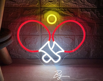 May include: A neon sign in the shape of a ping pong paddle and ball. The paddles are outlined in red, the ball is yellow, and the handles are white. The sign is against a brick wall.