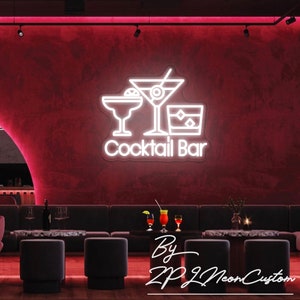 May include: A neon sign for a cocktail bar, featuring three drink glasses and the words "Cocktail Bar" in white. The sign is mounted on a dark red wall. The image also shows a bar setting with seating and tables.