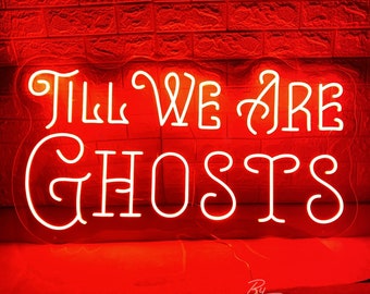 May include: A neon sign with the words "Till We Are Ghosts" in white script. The sign is encased in a clear border and glows brightly against a red brick wall. The sign is signed "By ZPJ Neon Custom".
